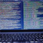 Software code displayed across a monitor in front of computer keyboard