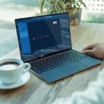 Laptop on table displaying website next to a cup of coffee
