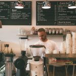 Small business owner behind coffee shop counter representing custom software and outsourcing
