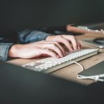 Hands typing on computer keyboard representing software development
