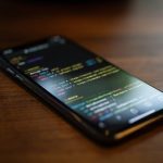 Smartphone with black screen displaying text on wooden desktop