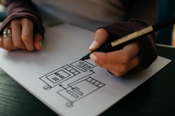 Writer draws infographic diagram on white sheet of paper while holding pen