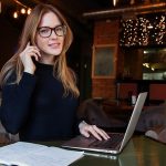 Software manager in front of laptop speaking on mobile phone