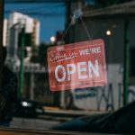 Shop sign behind glass shop door of a small business reads Come in We're Open