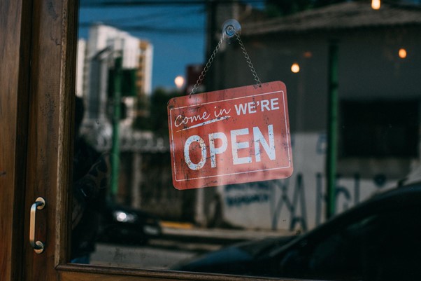 Shop sign behind glass shop door of a small business reads Come in We're Open
